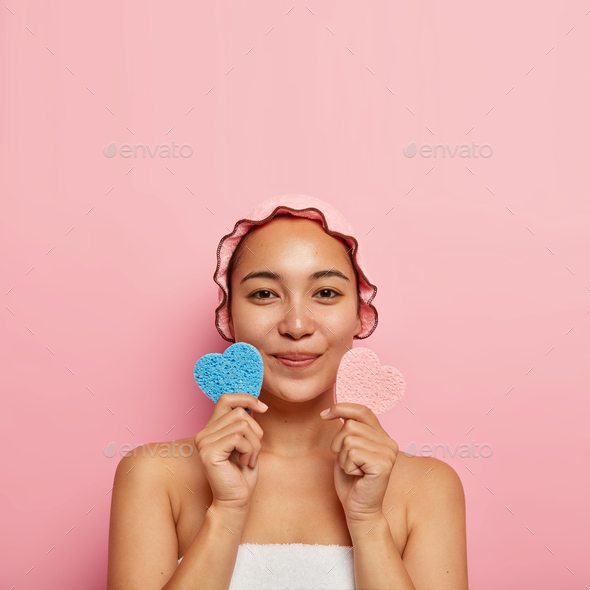 Skin care concept. Beautiful satisfied korean girl holds pink and blue cosmetic sponges in shape of
