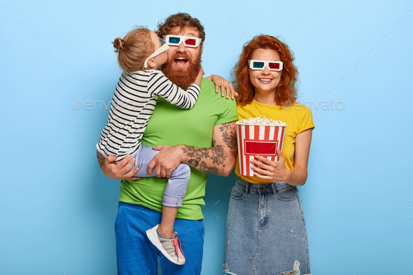 Family portrait of three redhead members wears 3d glasses and eat popcorn, being in cinema, come on