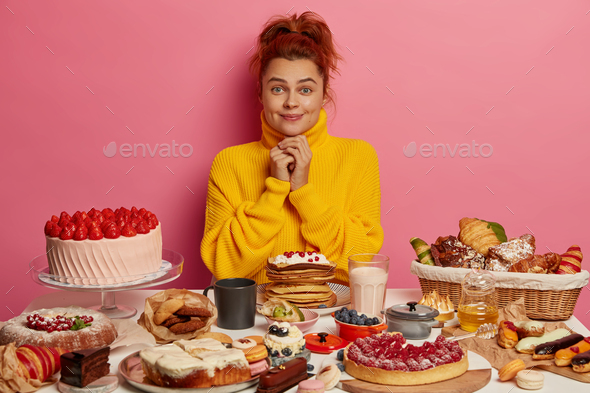 I want to eat it so much! Redhead young girl keeps hands together, has happy expression, wears yello