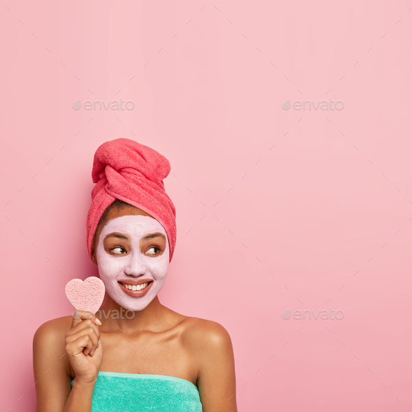 Pretty young dark skinned model has well cared skin, wears facial mask for reducing dark dotes and b