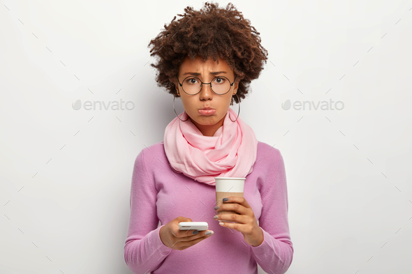 Unhappy African American woman purses lower lip, feels dejected as boyfriend doesnt call in time, ho - Stock Photo - Images