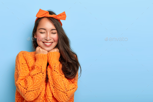 Portrait of cheerful mixed race woman has shy satisfied expression, smiles broadly, shows white teet