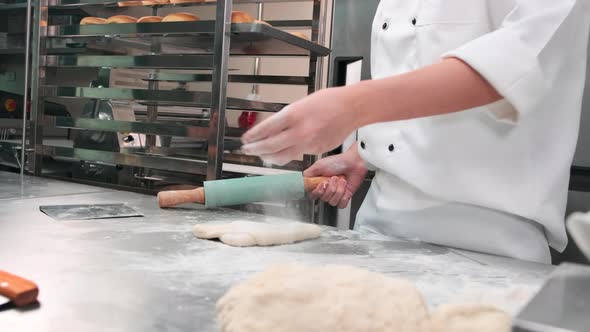 Chef is preparing pastry dough, baking bakery food on a stainless steel table. alt