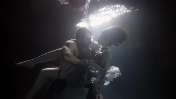 Lovers in Deepness of Pool in Dark Water Man Is Hugging Young Woman Love and Passion alt