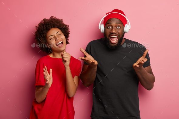 Cheerful crazy couple wear big headphones for listening music, being full of energy, dance actively