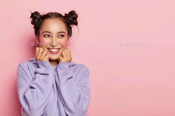 Studio shot of pretty smiling Asian woman with dark hair, two knots, wears purple loose jumper, stan