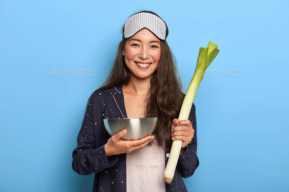 People, wellness and healthy eating concept. Happy mixed race woman holds raw green leek, returns fr