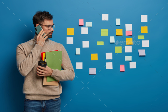 Caucasian man has creative approach to organizing work, leaves colorful stickers on wall, discusses