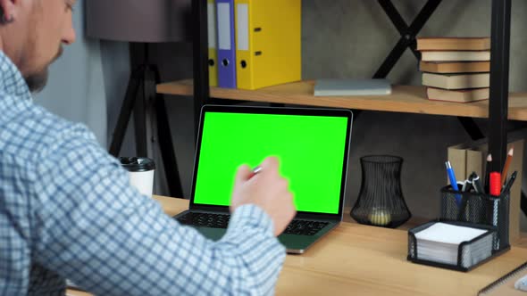 Green screen laptop concept: man student sitting in office writes in notebook alt