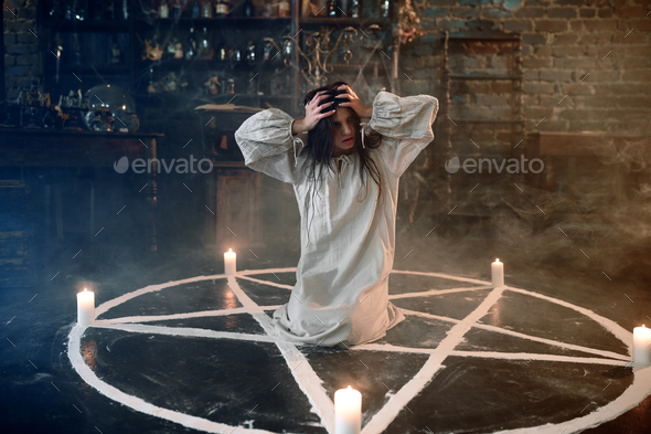Scary demonic woman sitting in the magic circle