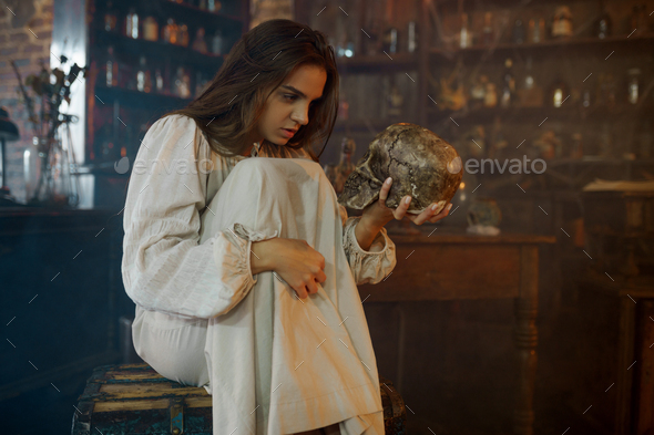 Scary demonic woman holds human skull, exorcism