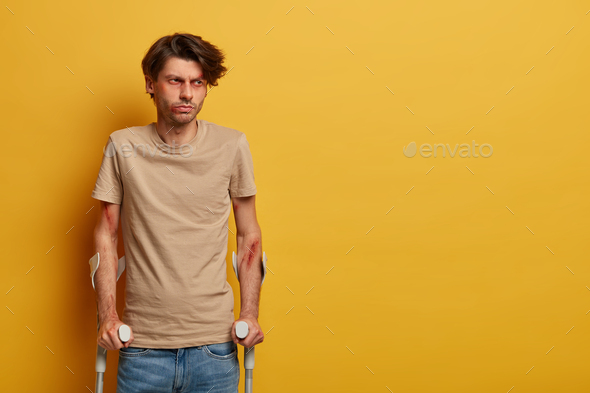 Disabled injured man has broken or sprained ankle, poses with crutches, recovers after dangerous rid