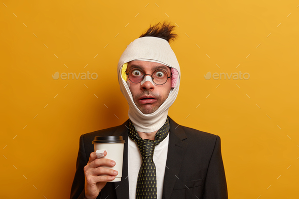 Portrait of shocked businessman has various traumas after hangover, swollen face and bruises under e