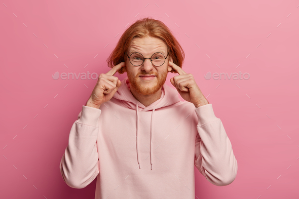 Image of stressed redhaired man bothered by loud neighbour, tells turn off music, unwilling hear awf