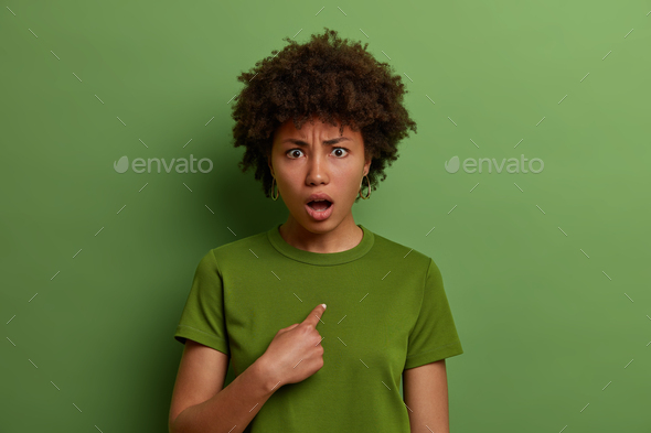 Startled Afro American woman looks questioned and confused with disbelief, shocked to be picked or a