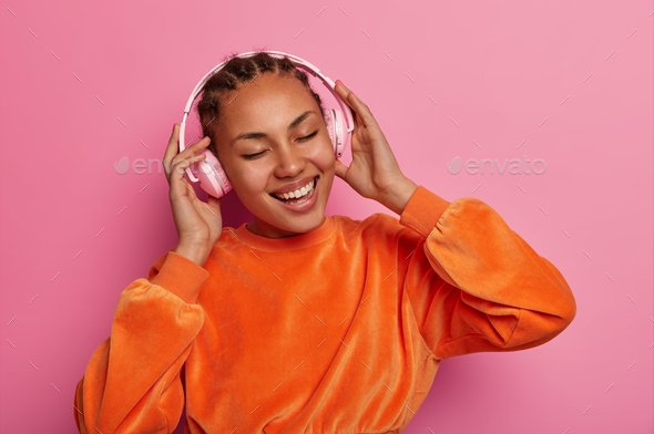Modern life, fun and entertainment concept. Happy ethnic girl listens song or cool track in stereo h