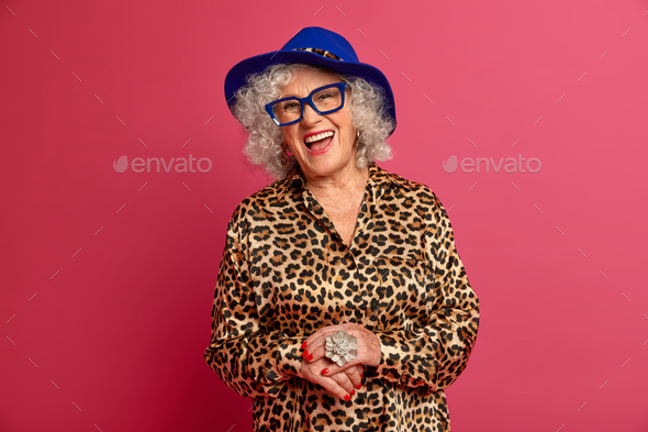 Happy old age. Fashionable woman pensioner dressed in stylish leopard shirt and hat, smiles joyfully