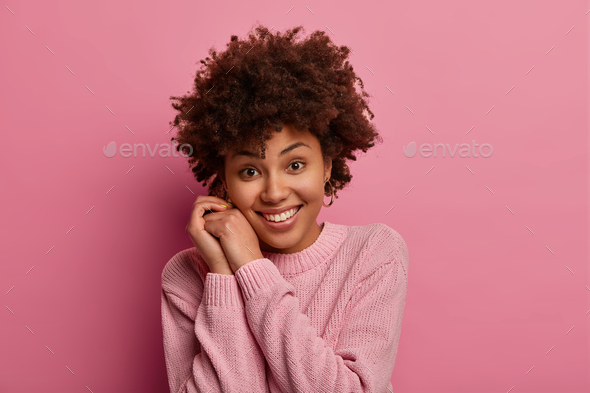 Photo of pretty young tender woman with Afro hair smiles gently, keeps ...