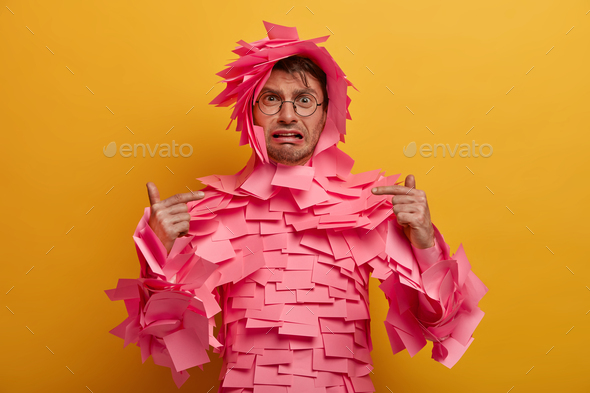 Gloomy depressed man points at himself, has problems, cries from despair, poses in paper costume mad