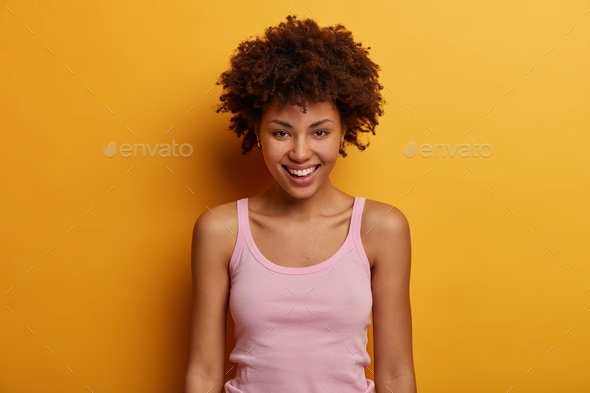 Portrait of good looking sincere woman looks positively at camera, has toothy smile, direct gaze at