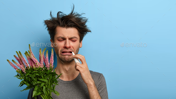 Seasonal allergy concept. Sick man has messy hair, suffers from hay fever, going to sneeze, reacts o