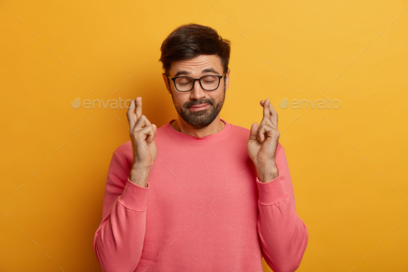 Hopeful bearded man crosses fingers wants get job, searches career opportunities awaits for result a