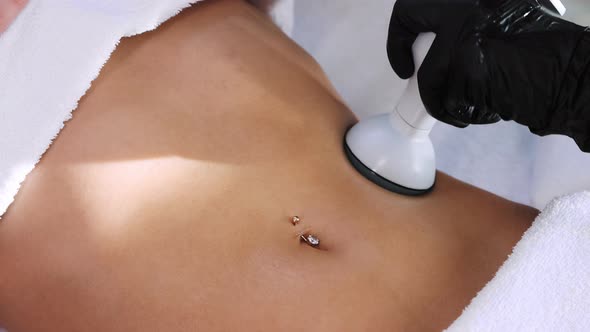 Electric Body Massage  Therapist Using a Device on the Stomach with Piercing of Her Woman Client alt