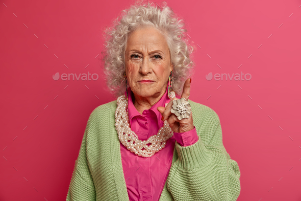 Attention to this information. Serious confident old woman raises finger, gives advice with convince