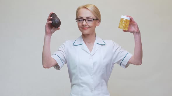 Nutritionist Doctor Holding Organic Avocado Fruit and Jar of Medicine or Vitamin or Omega 3 Capsules alt