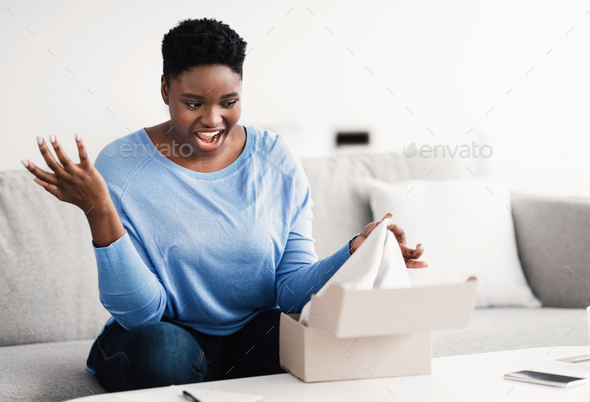 Frustrated black woman unpacking wrong box, delivery mistake