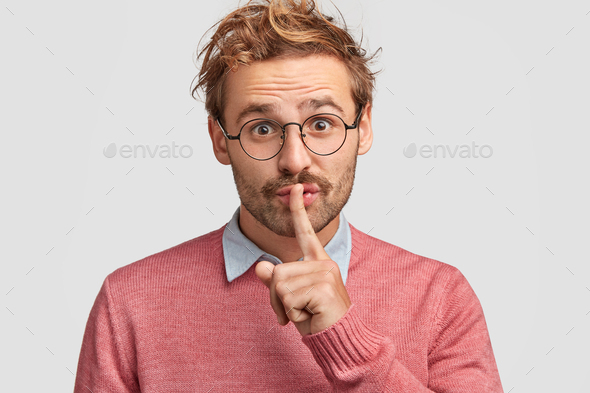 Attractive male tells secret to close friend, hopes for loyalty and silence, makes hush gesture, wea