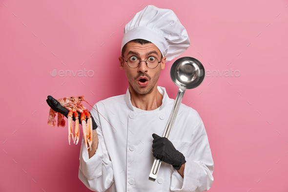 Scared unexperienced male chef afraids of giving master class how to cook seafood dish, wears white