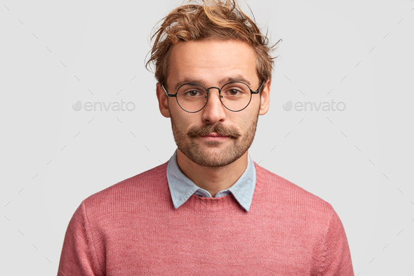 Serious male teacher with confident clever look, has beard and mustache, listens pupil`s answer, wea