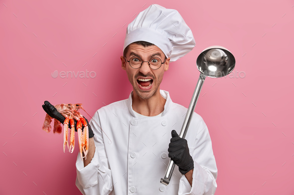 Angry irritated chef screams as has deadline to cook dinner, poses with crayfish and ladle, shouts a