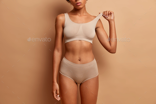 Femine beauty lines concept. Slim woman with dark skin flat stomach wears  high waist panties and bra Stock Photo by wayhomestudioo