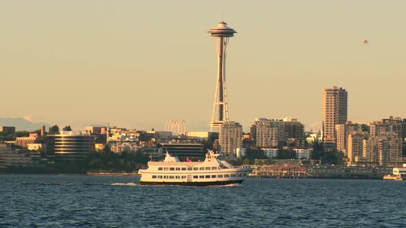 Sunset at Elliot Bay in Seattle with ferry crossing in front of the Space Needle. alt
