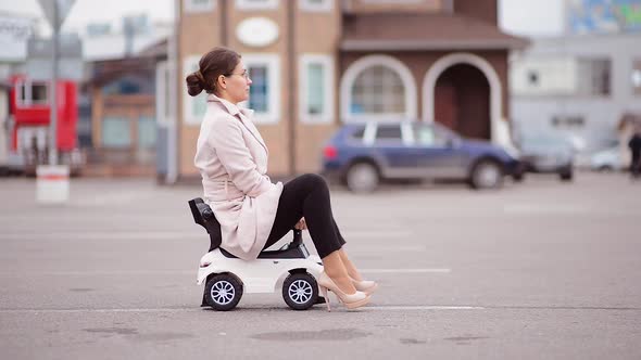 a young woman in a coat in a child car rides in the parking lot alt