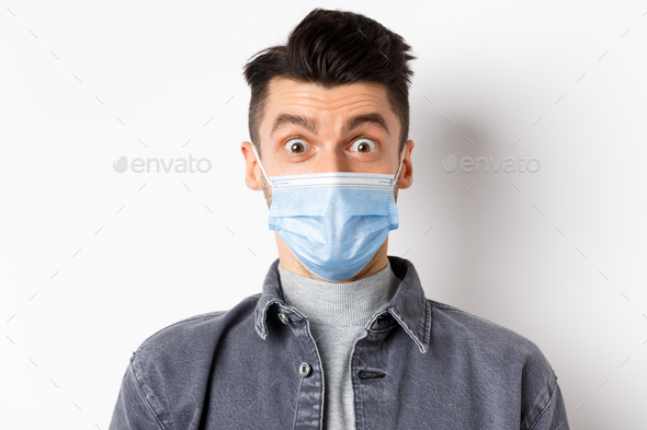 Pandemic lifestyle, healthcare and medicine concept. Portrait of surprised man in face mask raising