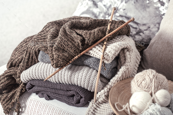 Vintage wooden knitting needles and threads for knitting on a cozy sofa  with pillows and sweaters Stock Photo by puhimec