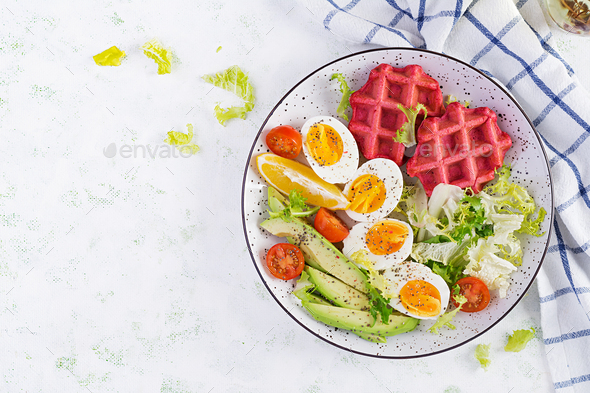 Breakfast with beetroot waffles, boiled egg, tomato and slice avocado