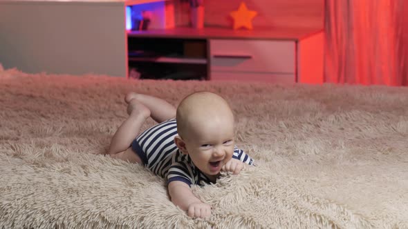 Little Happy Baby boy lies on tummy and smiling at the camera. Newborn Playful and energetic child. alt