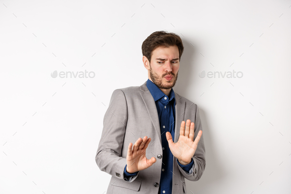 Stay away. Reluctant businessman step back with concerned disgusted face, raising hands to block bad