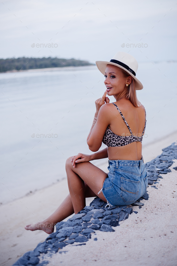 young european woman in leopard top bikini, jean shorts and classic white hat