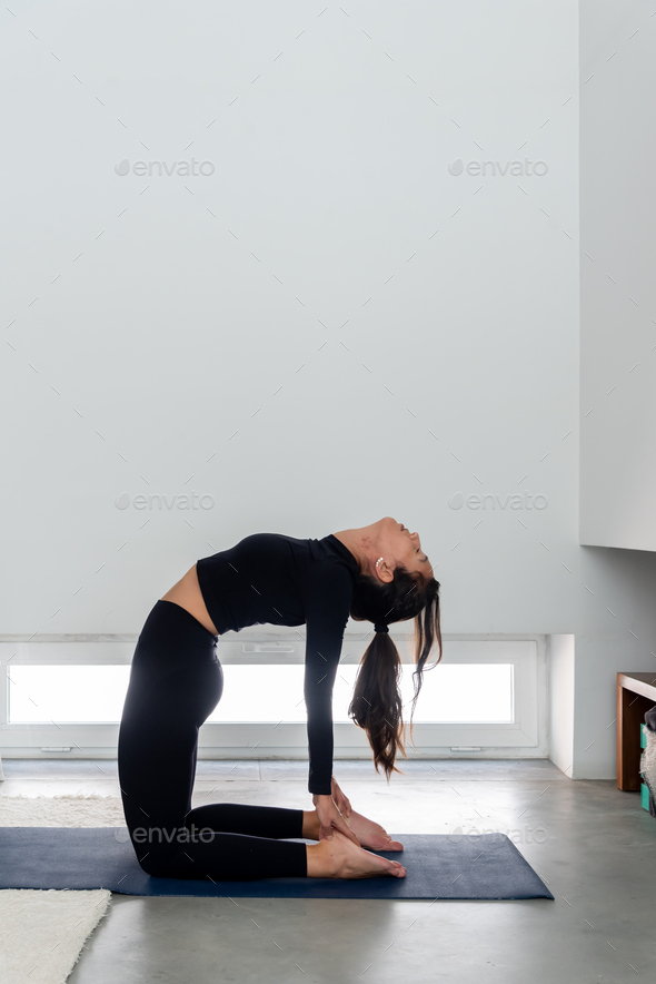 Young smiling woman in one hand Ustrasana camel yoga pose. Slim woman  practicing yoga at home Stock Photo - Alamy