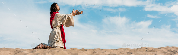 panoramic shot of jesus praying on knees in desert against sky