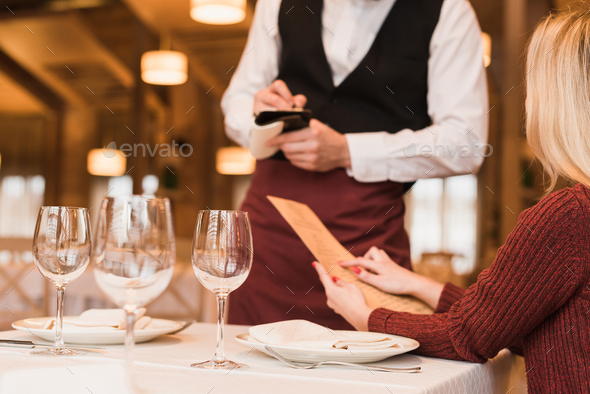 Cropped image of Waiter writing down the order of customer at the restaurant