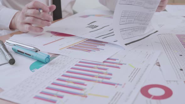Businessman works with charts in the office at the table and signs documents alt