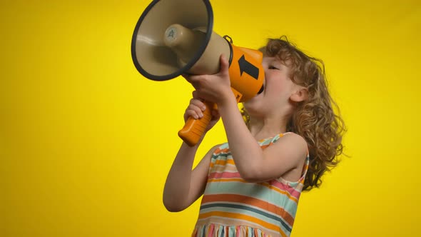 The Cute Little Girl in a Striped Dress is Creaming in a Megaphone and Laughing alt