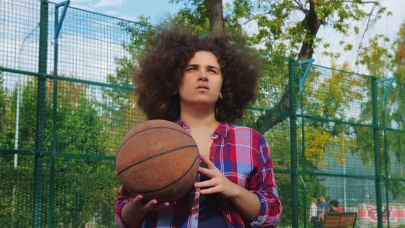 A Young Teenage Girl with an African Hairstyle Throws a Basketball Ball Into the Basket. alt