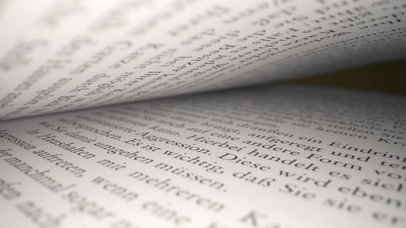 Macro dolly shot through old german book pages lighting by flashlight at night, zoom out. Camera Mov alt